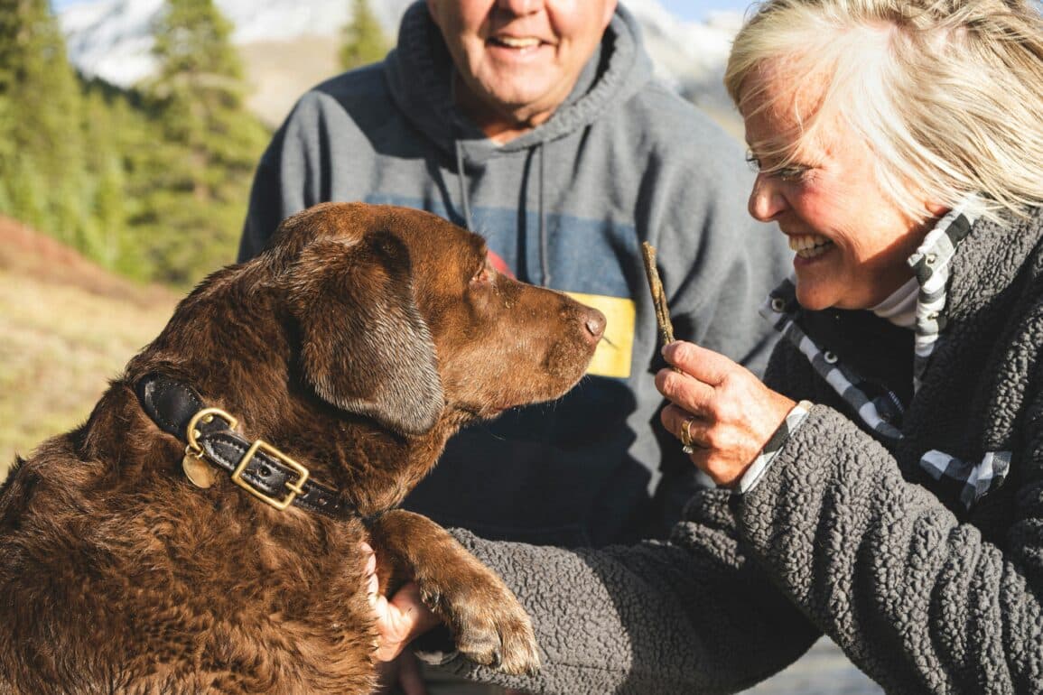 man and woman feeding their dog a treat