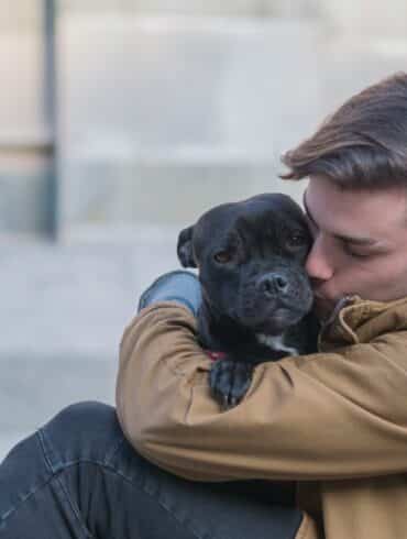 man hugging his dog outside