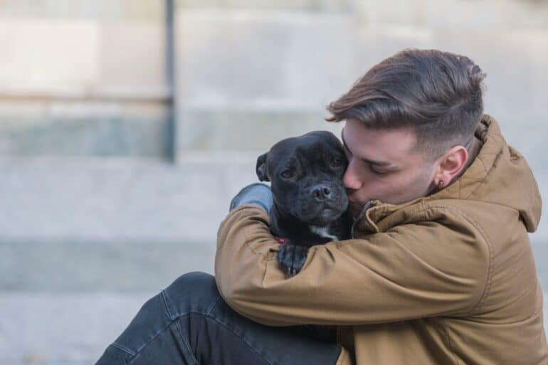 man hugging his dog outside