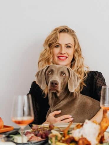 a blonde woman sitting at the table with her dog
