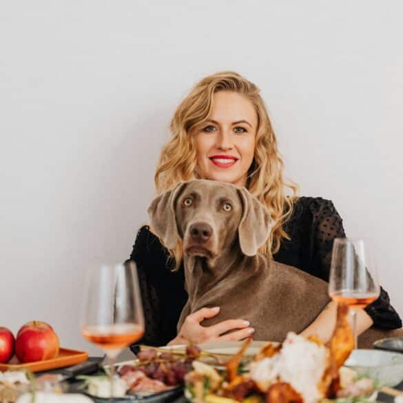 a blonde woman sitting at the table with her dog