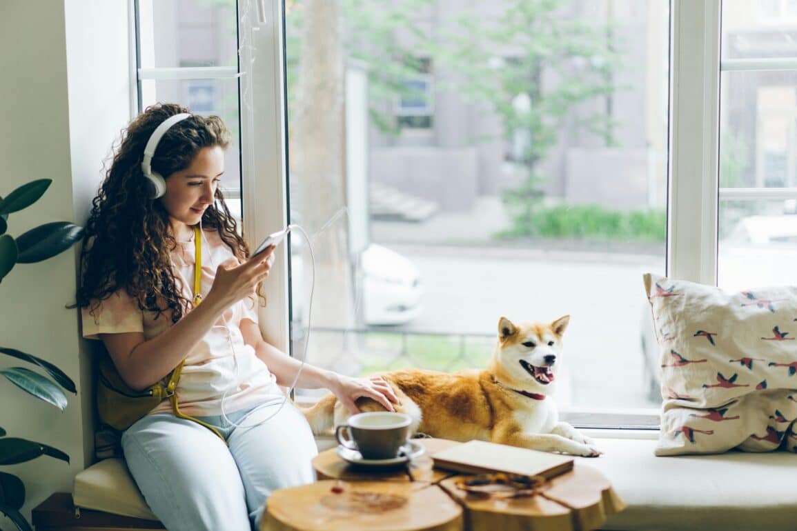 woman listening to music inside next to a dog