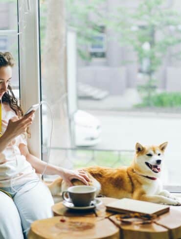 woman listening to music inside next to a dog