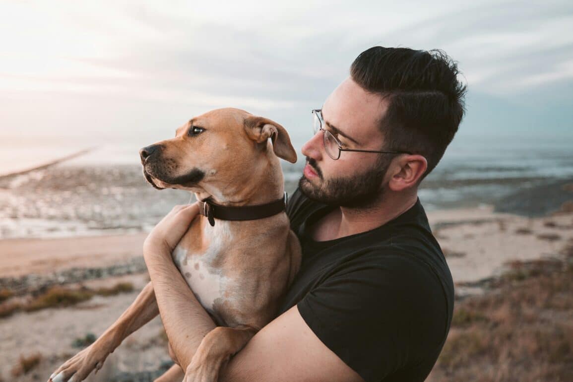 man holding his dog on the beach