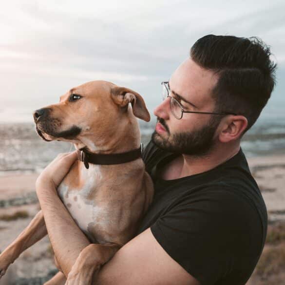 man holding his dog on the beach